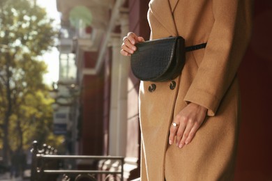 Young woman with stylish waist bag on city street, closeup. Space for text