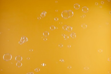 Photo of Many beautiful soap bubbles on orange background