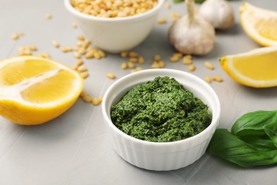 Photo of Bowl with basil pesto sauce on table