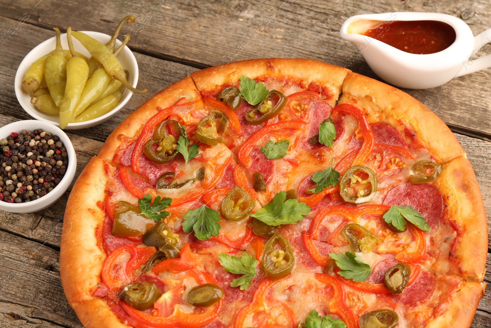 Photo of Delicious pizza Diablo and ingredients on wooden table, closeup