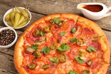 Photo of Delicious pizza Diablo and ingredients on wooden table, closeup