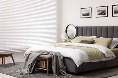 Photo of Window with horizontal blinds and comfortable bed in room