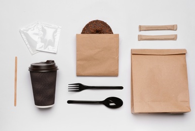 Flat lay composition with paper bags and different takeaway items on white background. Space for design