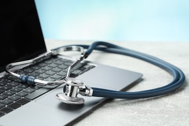 Photo of Stethoscope and modern laptop on grey table, closeup