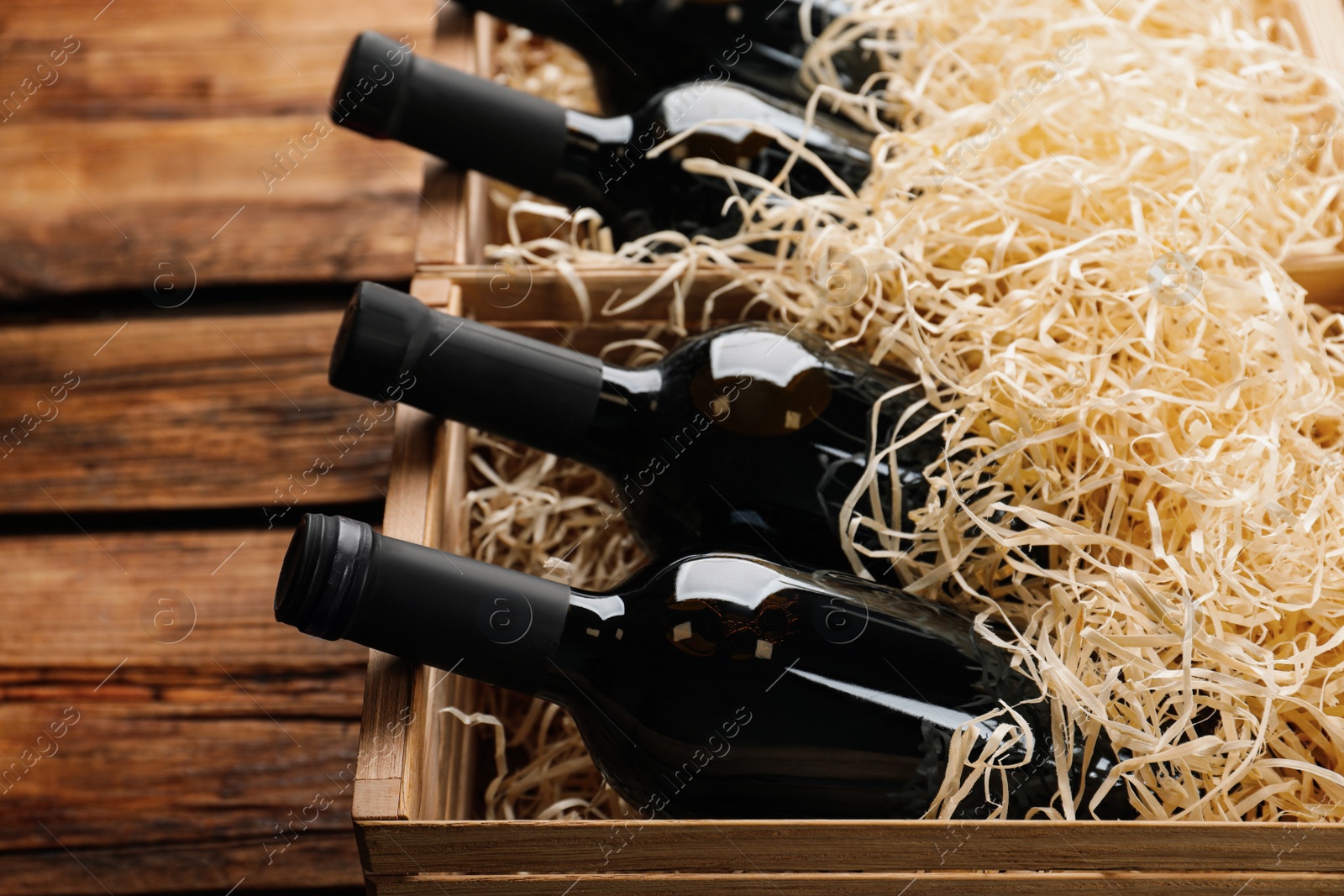 Photo of Crates with bottles of wine on wooden background, closeup