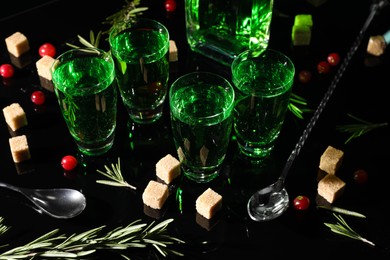 Absinthe in shot glasses, cranberries, rosemary and brown sugar on mirror table. Alcoholic drink