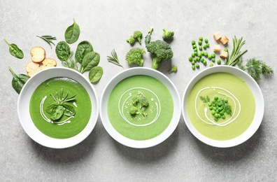 Photo of Dishes with different fresh vegetable detox soups made of green peas, broccoli, spinach and ingredients on table, flat lay