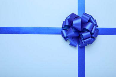 Photo of Ribbons with bow on light blue background, top view. Space for text