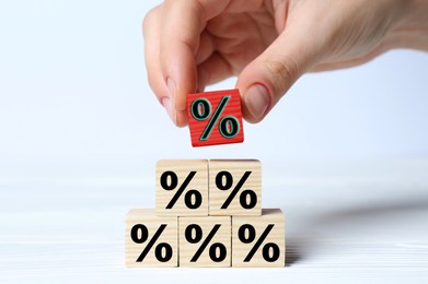 Image of Best mortgage interest rate. Woman putting red cube with percent sign on top of pyramid of others on white background, closeup