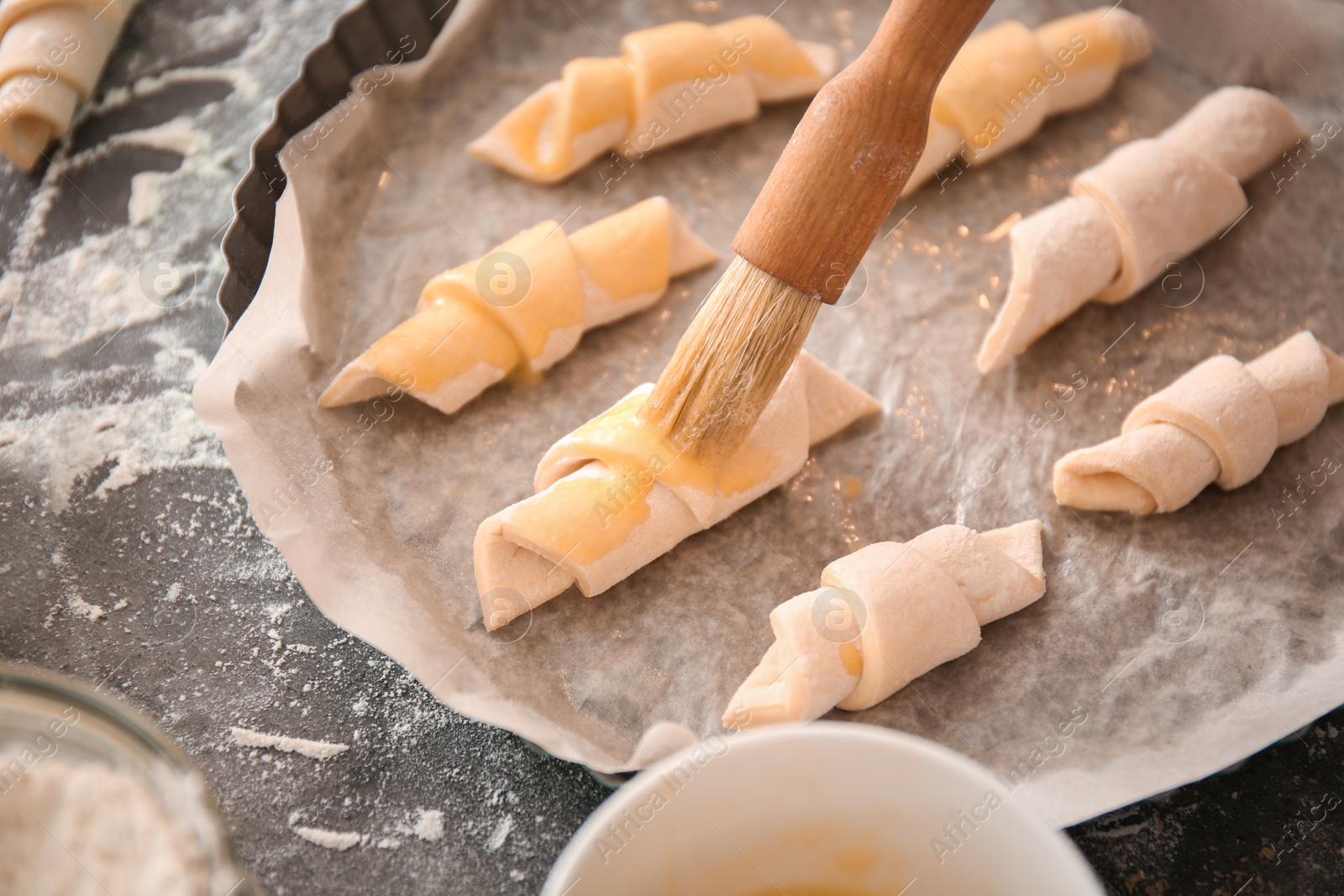 Photo of Spreading egg yolk on croissants, closeup