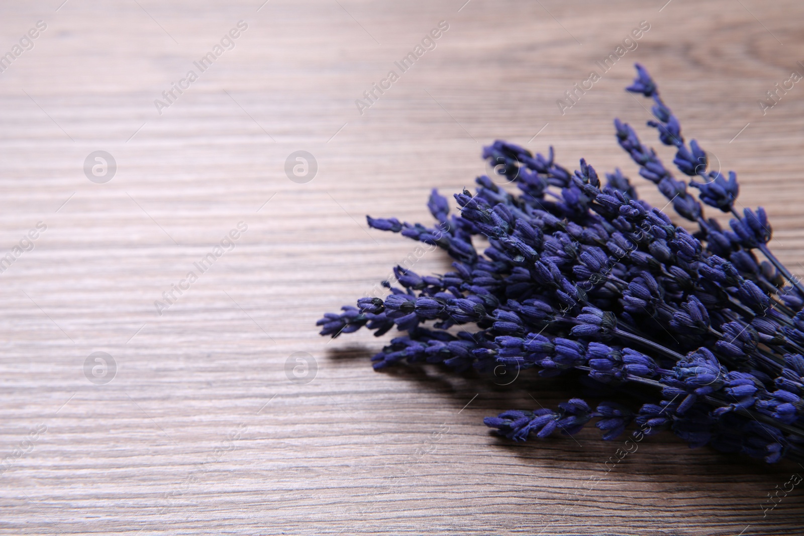 Photo of Bouquet of beautiful preserved lavender flowers on wooden table, space for text