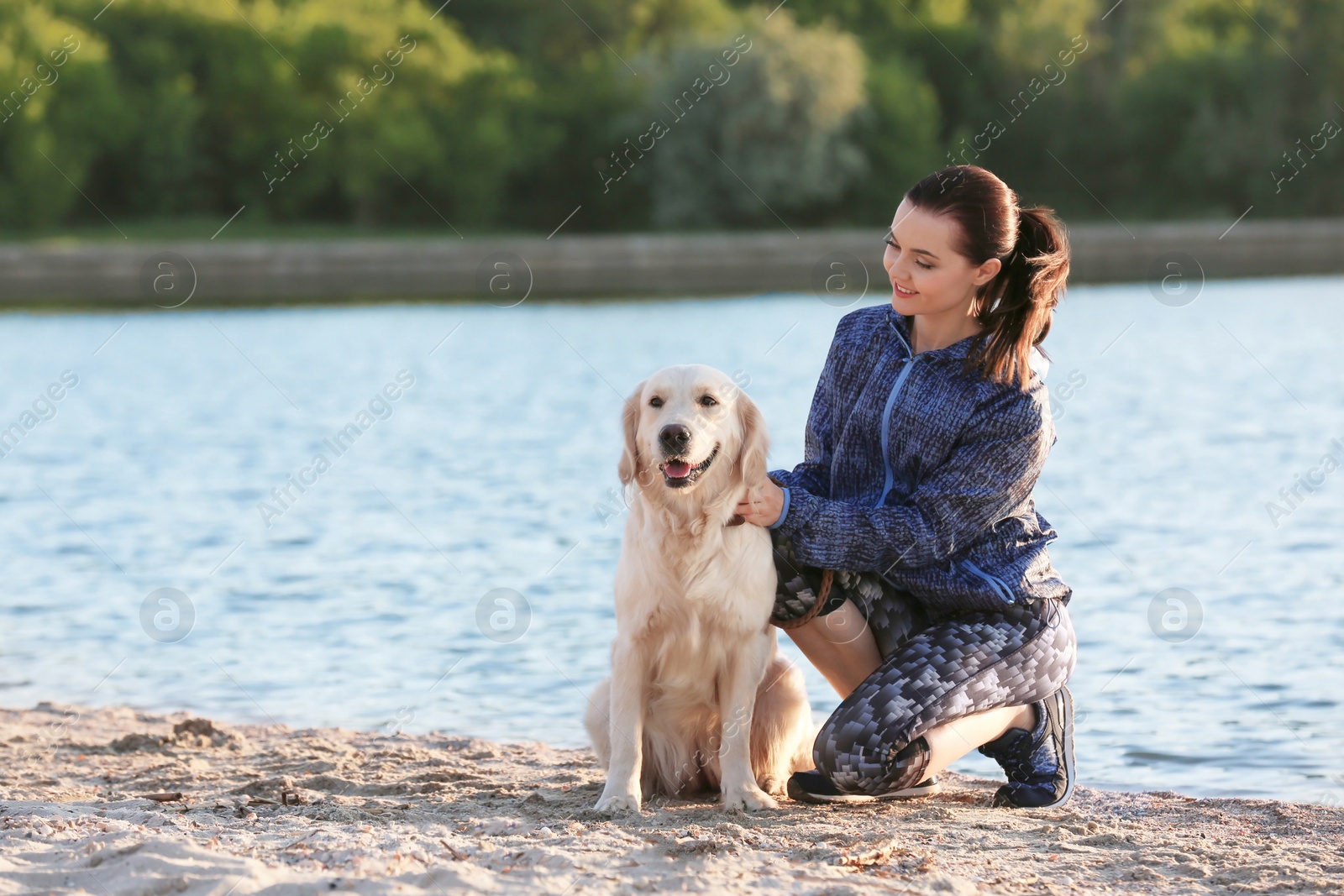 Photo of Young woman with her dog together on beach. Pet care