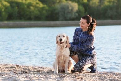 Photo of Young woman with her dog together on beach. Pet care