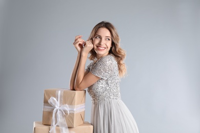 Photo of Beautiful young woman with Christmas presents on light grey background