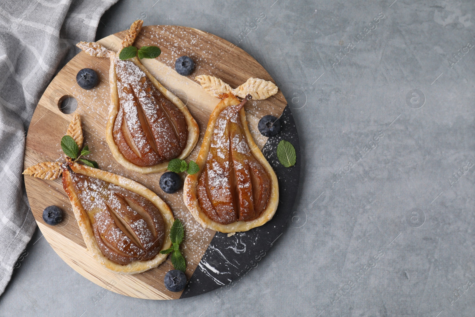 Photo of Delicious pears baked in puff pastry with powdered sugar served on grey table, top view. Space for text