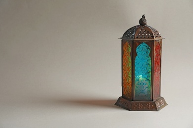 Photo of Muslim lamp with candle on light background. Fanous as Ramadan symbol