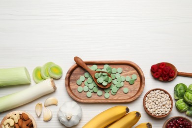 Many prebiotic pills and food on white wooden table, flat lay. Space for text