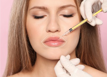 Young woman getting lips injection on pink background, closeup. Cosmetic surgery