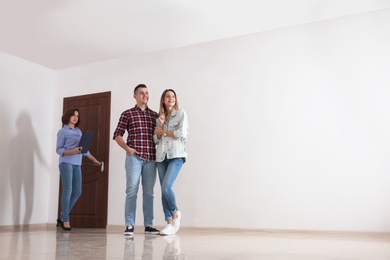 Photo of Real estate agent showing new apartment to young couple. Space for text