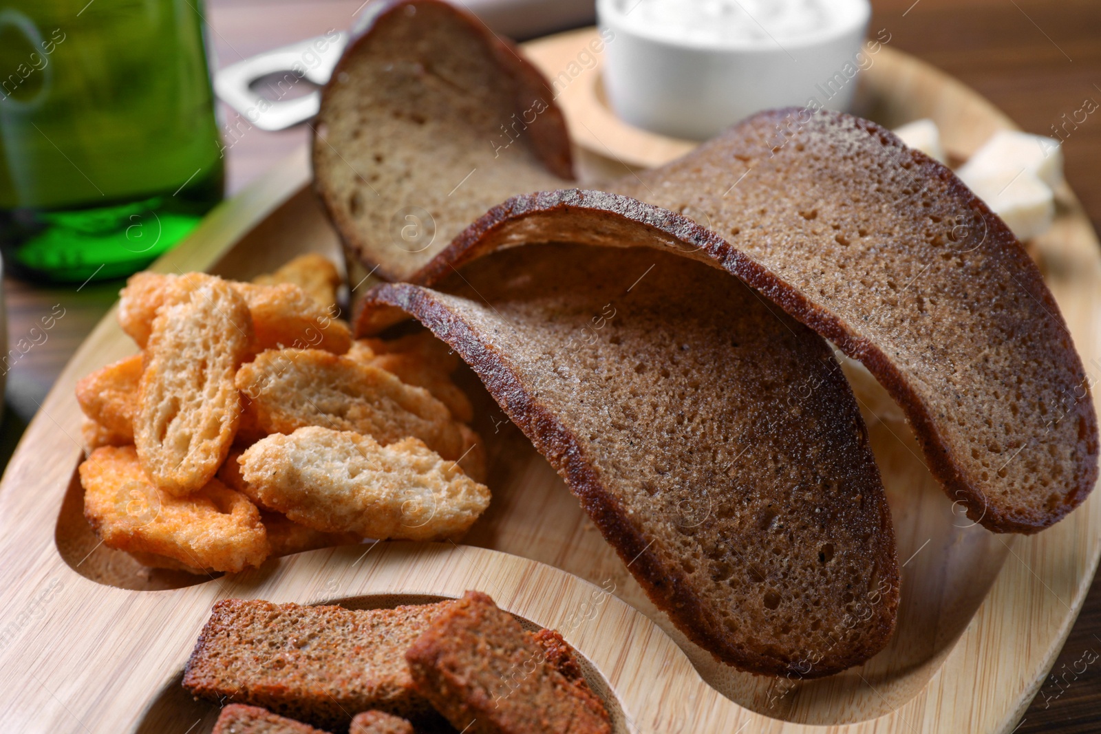 Photo of Wooden tray with different crispy rusks on table, closeup