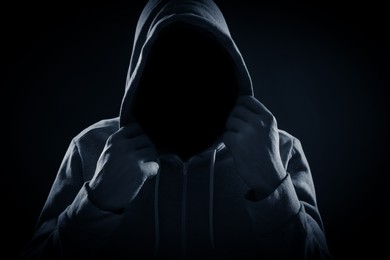 Image of Anonymous man in hood on black background