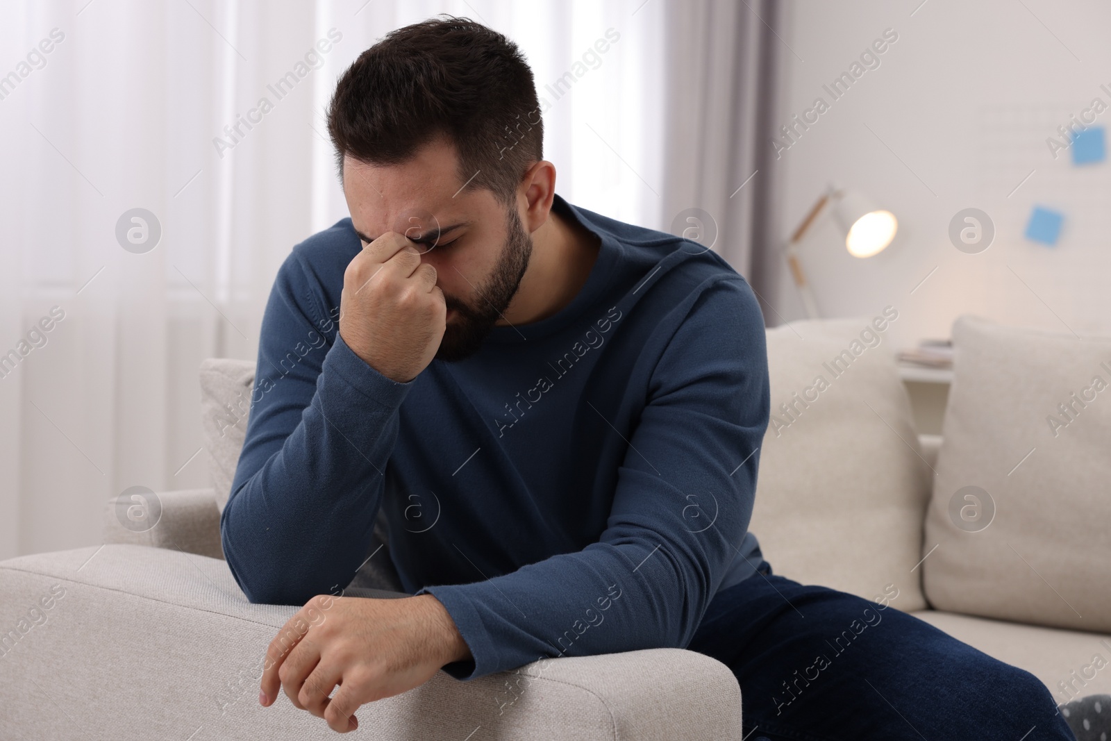 Photo of Man suffering from headache on sofa at home