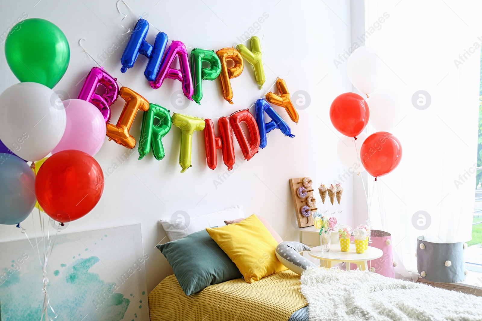 Photo of Phrase HAPPY BIRTHDAY made of colorful balloon letters in modern bedroom