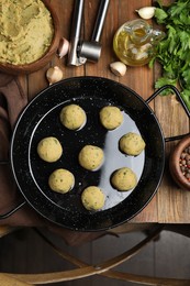 Raw falafel balls and ingredients on wooden table, flat lay