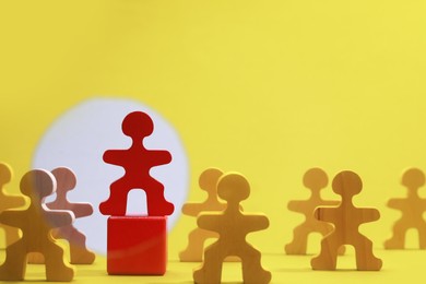 Wooden figures with red one on yellow background, space for text. Recruiter searching employee