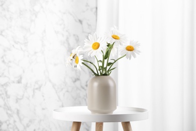 Beautiful tender chamomile flowers in vase on white table indoors