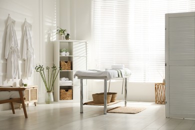 Photo of Stylish spa salon interior with massage table