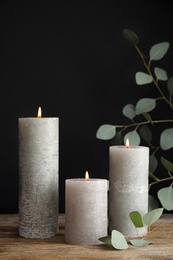 Photo of Composition with burning candles on table against black background