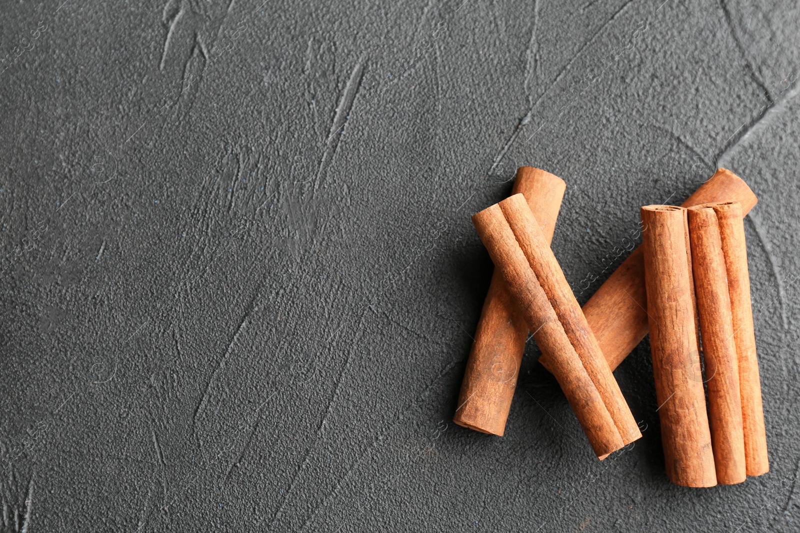 Photo of Aromatic cinnamon sticks on dark grey background