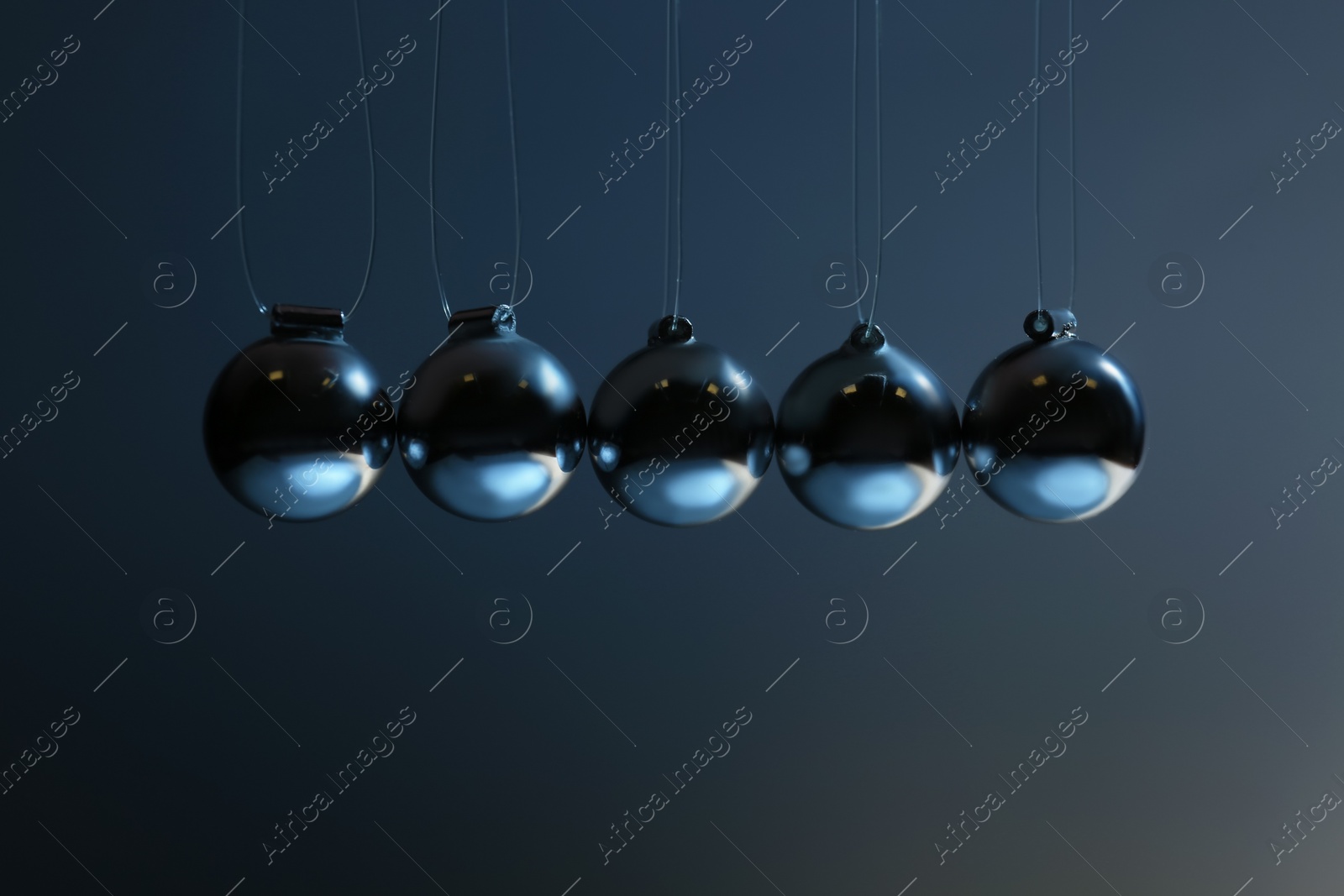 Photo of Newton's cradle on grey background, closeup. Physics law of energy conservation