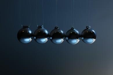 Photo of Newton's cradle on grey background, closeup. Physics law of energy conservation