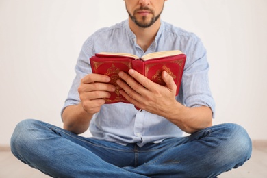 Photo of Muslim man reading Koran indoors, closeup view