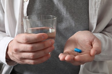 Photo of Man with glass of water and pill, closeup