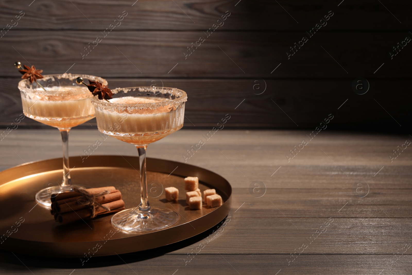 Photo of Delicious eggnog with cinnamon and anise on wooden table. Space for text