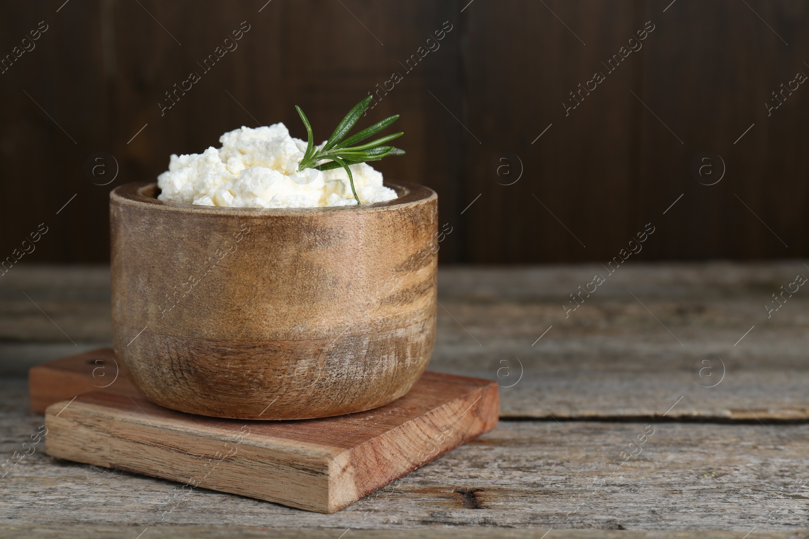 Photo of Delicious tofu cream cheese with rosemary in bowl on wooden table, space for text