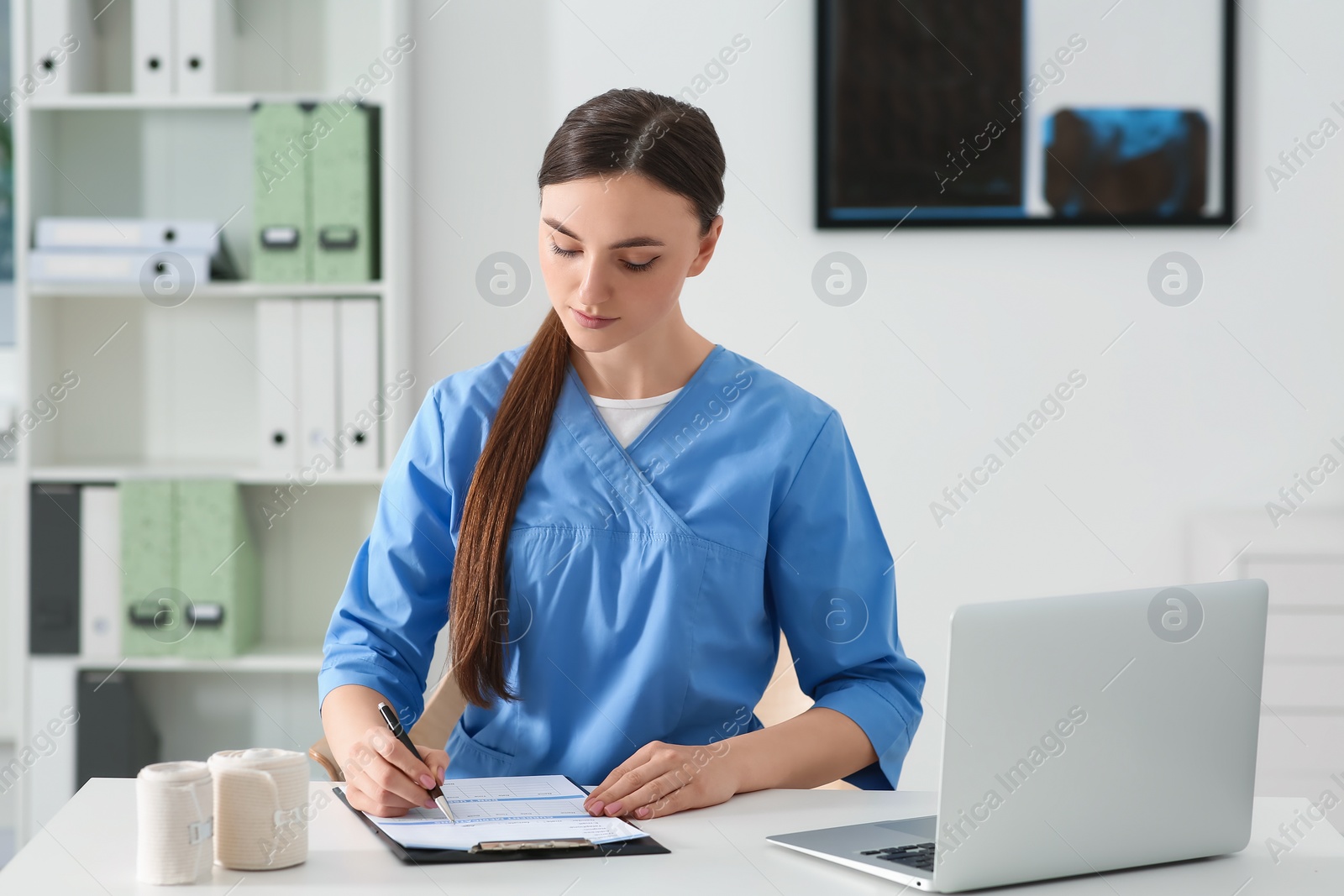 Photo of Doctor filling patient's medical card at table in clinic