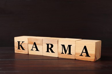 Word Karma made of cubes with letters on black wooden background