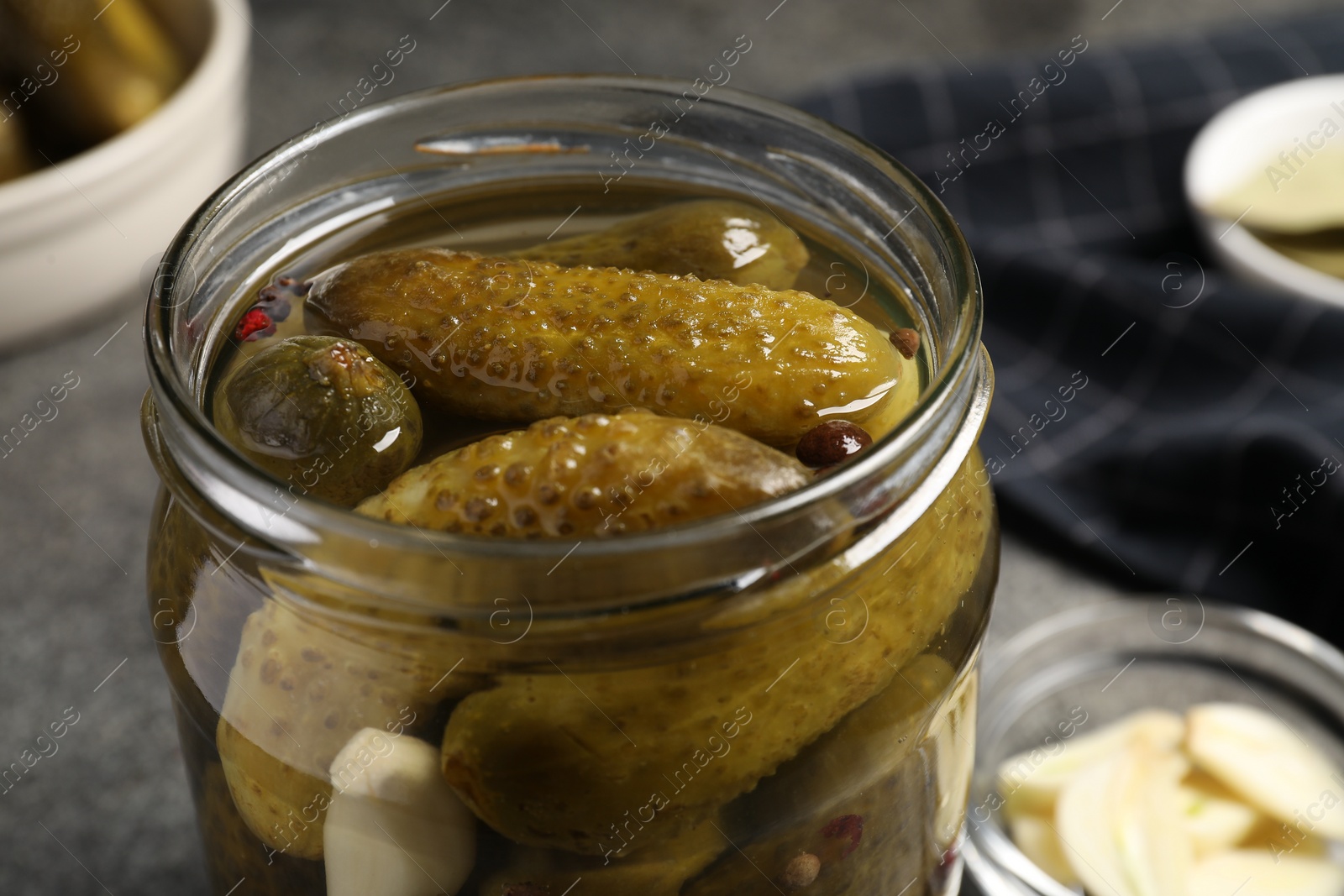 Photo of Tasty pickled cucumbers in glass jar on grey table, closeup