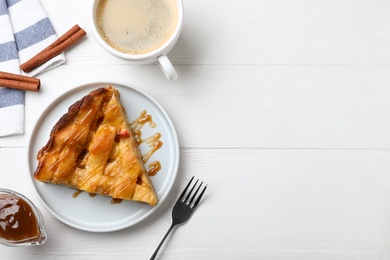 Slice of traditional apple pie served with coffee on white wooden table, flat lay. Space for text