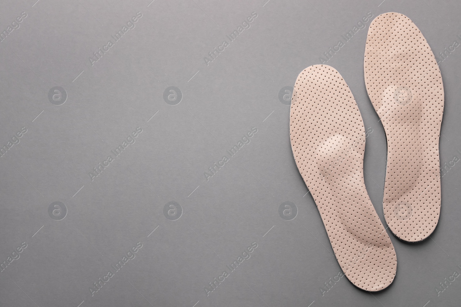 Photo of Beige orthopedic insoles on light grey background, flat lay. Space for text