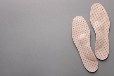 Beige orthopedic insoles on light grey background, flat lay. Space for text