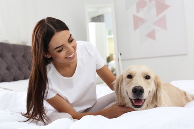 Photo of Young woman and her Golden Retriever dog on bed at home