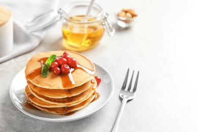 Stack of tasty pancakes with berries and syrup on table