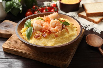 Fresh tasty shrimps, bacon, grits and basil in bowl on wooden table, closeup