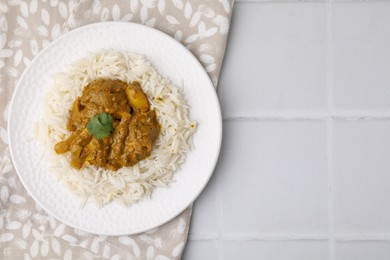 Photo of Delicious chicken curry with rice on white tiled table, top view. Space for text