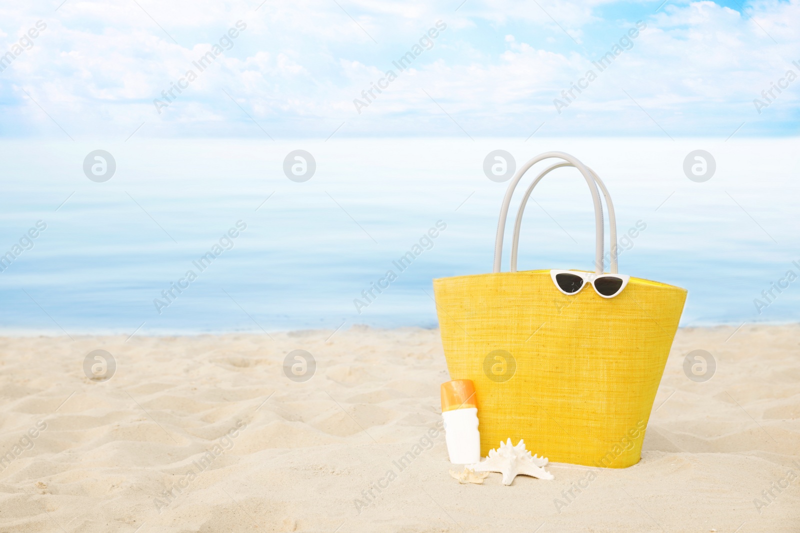 Photo of Stylish beach accessories on sand near sea. Space for text